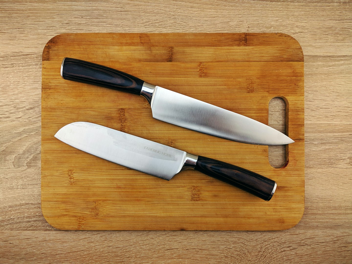 Chef's knife and santoku knife on a bamboo cutting board.