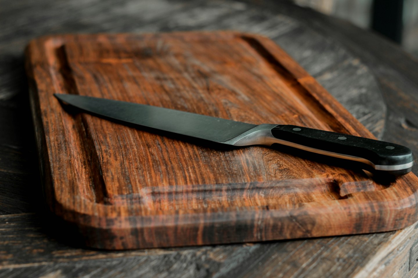 A chef knife rests on a wooden cutting board.