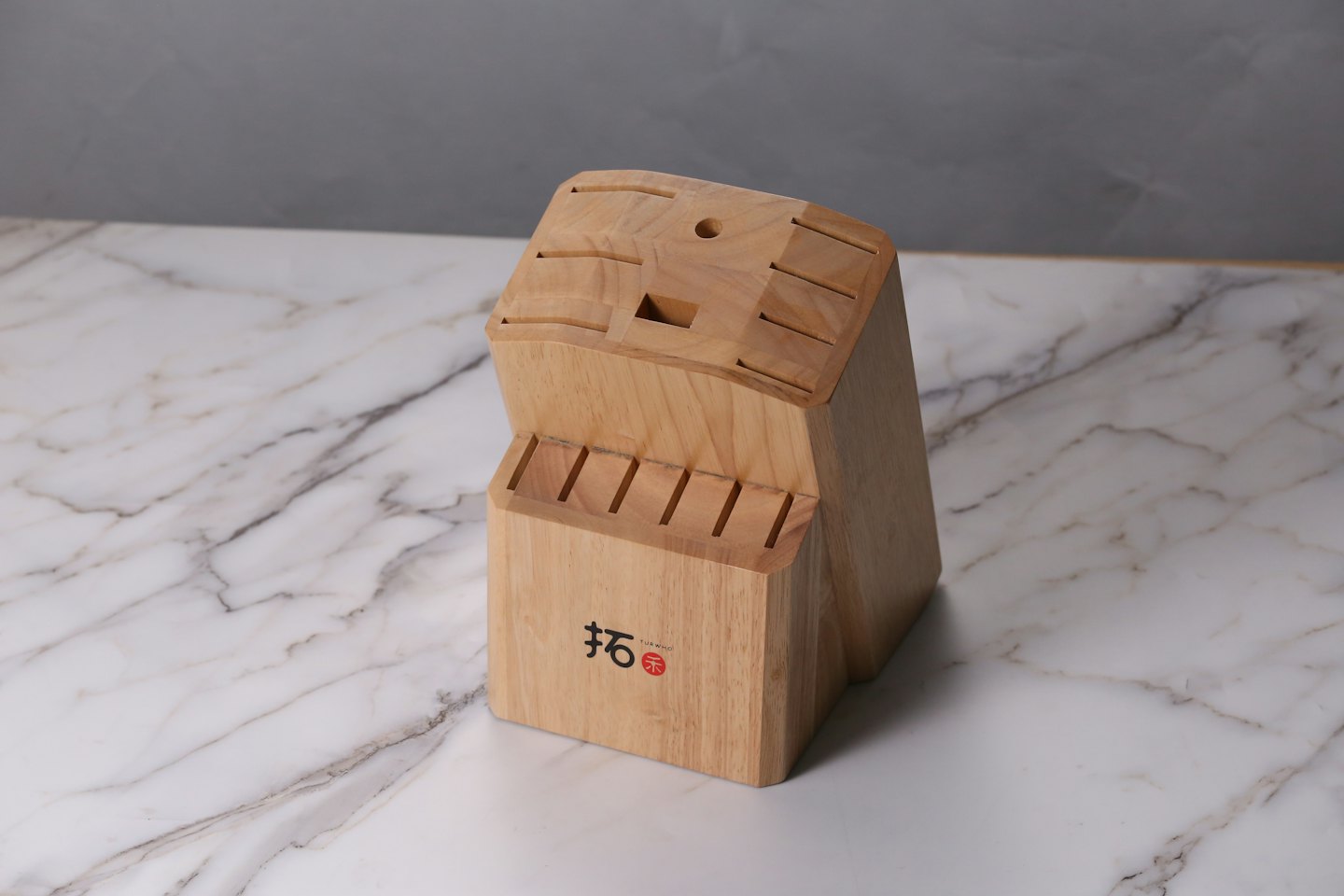 Wooden knife block sitting on a white marble countertop.